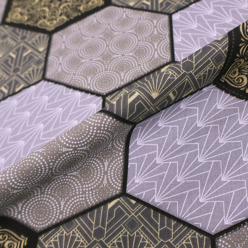 100% Cotton Great Value Fabric featuring a grey and cream hexagon print in which 4 different geometric designs are outlined in black.