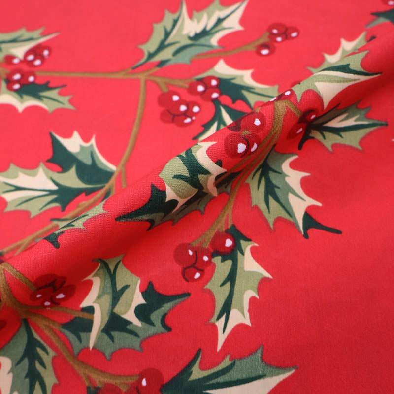 Red cotton Christmas fabric with green holly and berry print
