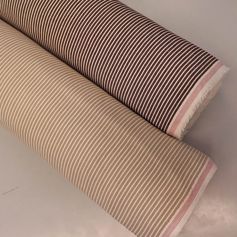 Two rolls of hickory striped denim fabric, one brown and white, one beige and white