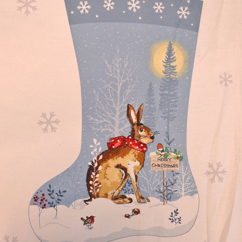 100% cotton Christmas stocking panel fabric featuring a brown rabbit wearing a red polka-dot scarf, sitting in a snowy winter landscape with bare trees, snowflakes, and a glowing moon. 