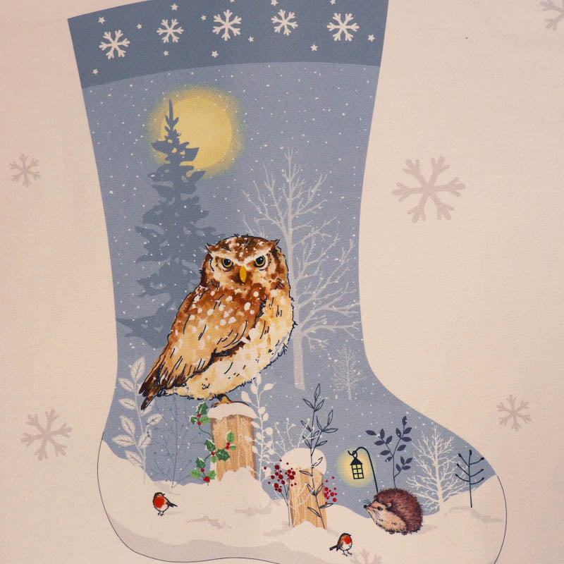 100% cotton Christmas stocking panel fabric featuring a brown and white spotted owl perched on a snowy landscape with trees, a glowing moon, robins, and a hedgehog, set on a pale blue and white background with snowflake motifs.