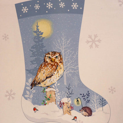 100% cotton Christmas stocking panel fabric featuring a brown and white spotted owl perched on a snowy landscape with trees, a glowing moon, robins, and a hedgehog, set on a pale blue and white background with snowflake motifs.