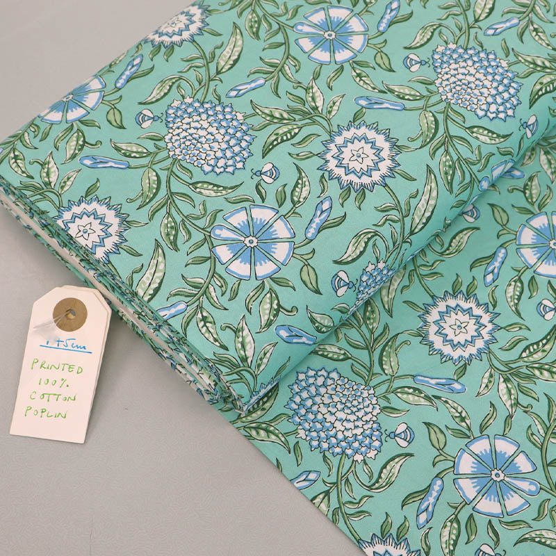 100% Cotton poplin fabric featuring a Digitally Printed pale blue and white floral and bee design with green leaves on a mint green background. 