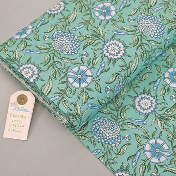  100% Cotton poplin fabric featuring a Digitally Printed pale blue and white floral and bee design with green leaves on a mint green background. 