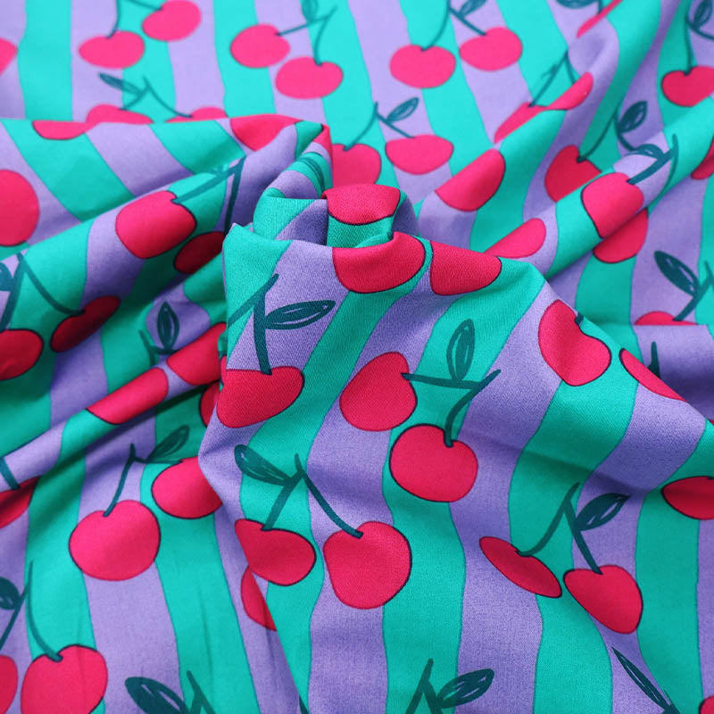 100% Cotton Poplin Fabric - Cherry Print
with red cherry print on a purple and green striped background.