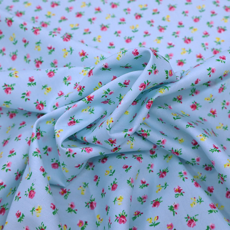 100% Cotton Ditsy Floral Poplin Fabric - small pink and yellow flowers on a pale blue background