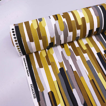  100% Cotton Great Value Cotton Fabric  with vertical stripes almost like brush strokes in brown, yellow, grey and black on a white background. 