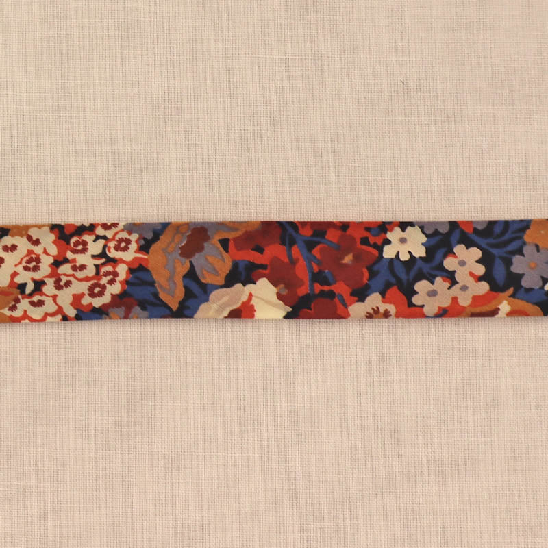 100% Cotton Liberty Fabric Bias Binding featuring a floral print in dark red, orange, blue and cream on a dark navy background