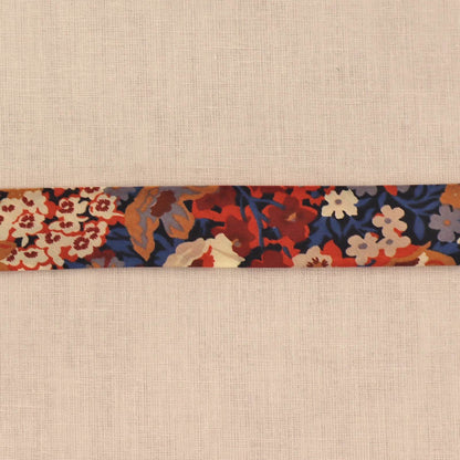 100% Cotton Liberty Fabric Bias Binding featuring a floral print in dark red, orange, blue and cream on a dark navy background