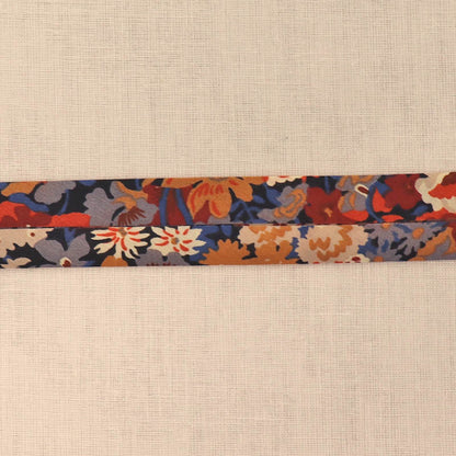 100% Cotton Liberty Fabric Bias Binding featuring a floral print in dark red, orange, blue and cream on a dark navy background