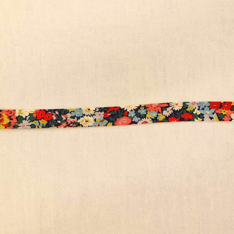 100% Cotton Liberty Fabric Bias Binding in Thorpe C featuring a vibrant floral print in coral, yellow, blue and green on a dark navy background