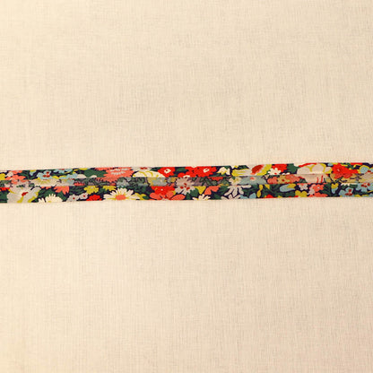 100% Cotton Liberty Fabric Bias Binding in Thorpe C featuring a vibrant floral print in coral, yellow, blue and green on a dark navy background