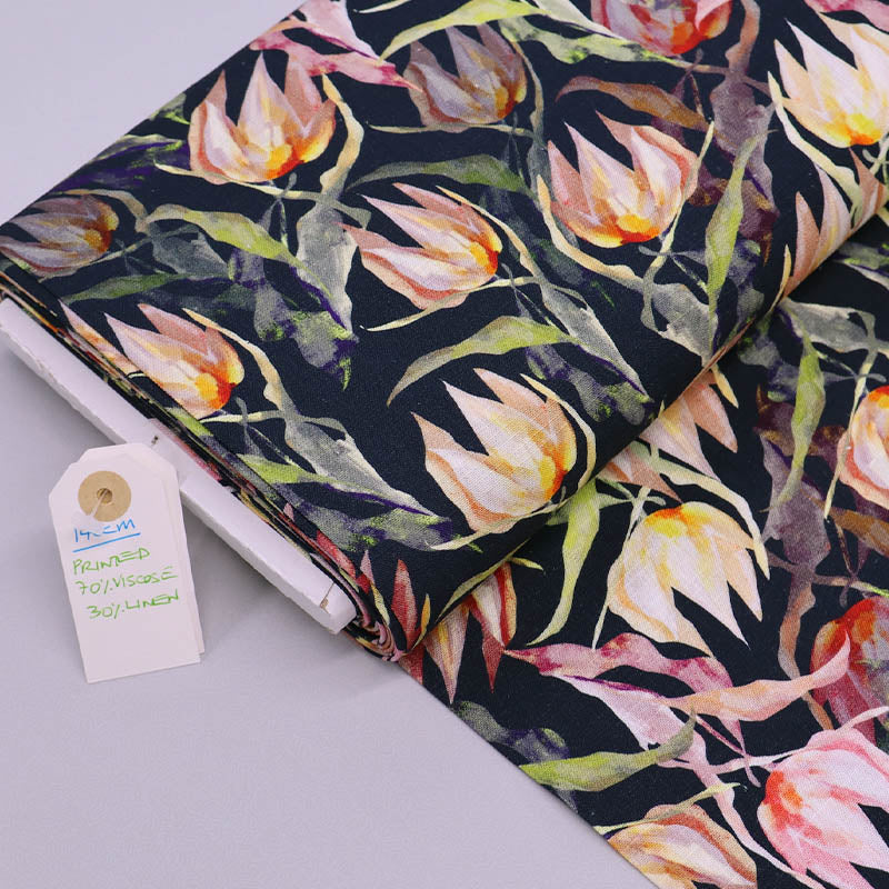 70% Viscose 30% Linen blend Fabric - Dark Blue Floral featuring a watercolour style floral print in peach yellow and orange with green leaves on a dark navy blue background.