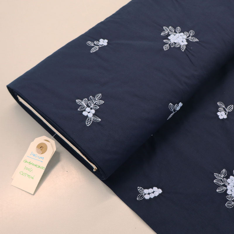 100% Cotton Embroidered Cotton Floral Fabric featuring pale blue floral and leaf motifs on a dark blue light weight cotton base cloth