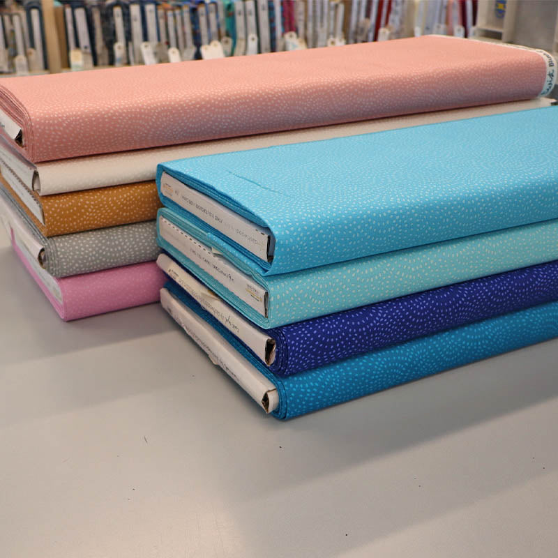 100% Cotton Quilting Blender Fabrics in 9 colours with a subtle print of white spots in a spiral on a plain coloured background.