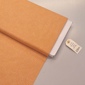 100% Cotton Orange Blender Fabric featuring a subtle print of white spots in a spiral on a soft orange background.