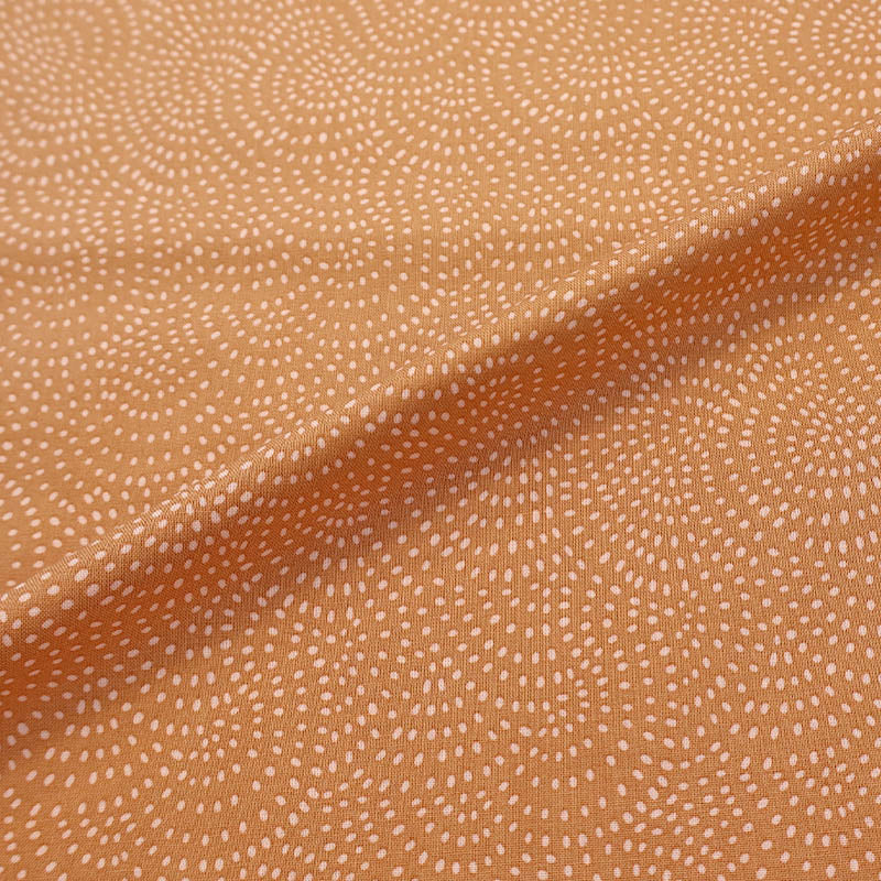 100% Cotton Orange Blender Fabric featuring a subtle print of white spots in a spiral on a soft orange background.