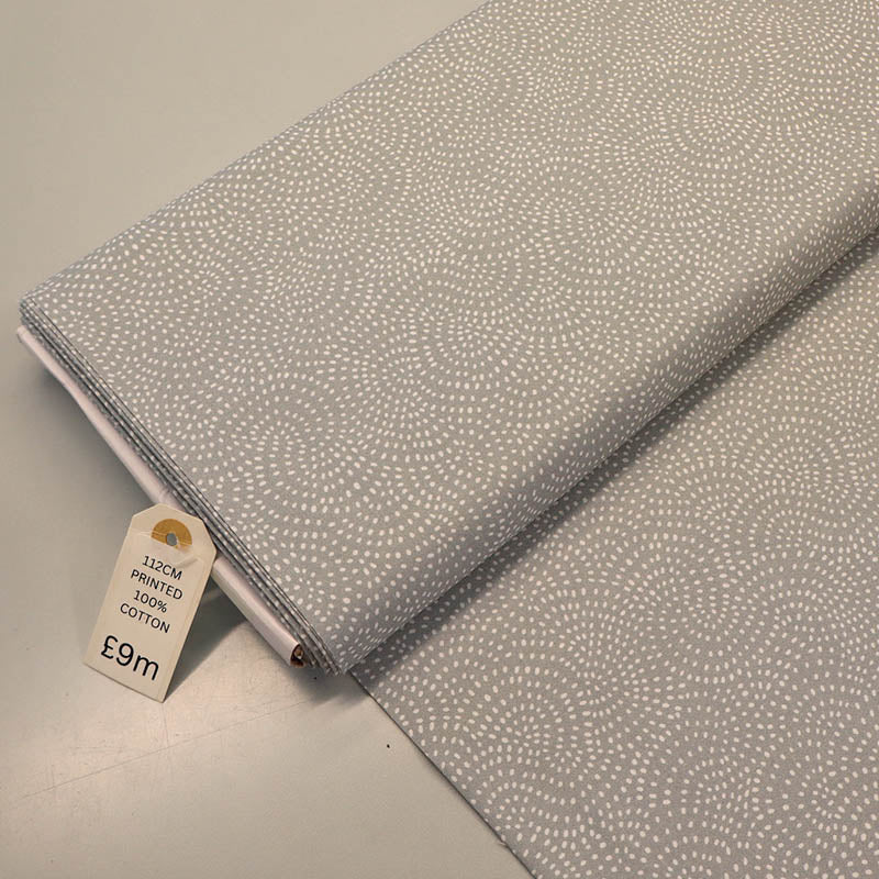 100% Cotton Pale Grey Blender Fabric featuring a subtle print of white spots in a spiral on a pale grey background.