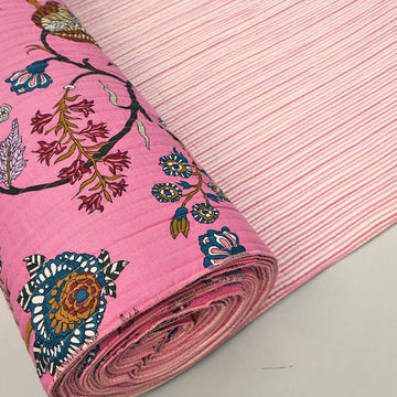 Quilted 100% Indian cotton fabric with a bold floral design in pink, blue and brown on a sugar pink background on one side and a fine pale pink and white stripe on the reverse.