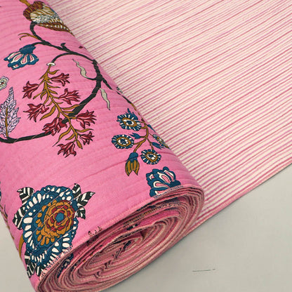 Quilted 100% Indian cotton fabric with a bold floral design in pink, blue and brown on a sugar pink background on one side and a fine pale pink and white stripe on the reverse.