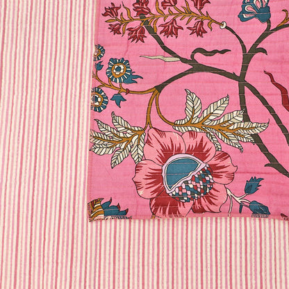 Quilted 100% Indian cotton fabric with a bold floral design in pink, blue and brown on a sugar pink background on one side and a fine pale pink and white stripe on the reverse.