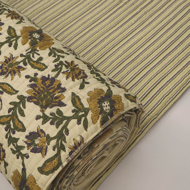 Quilted 100% Indian cotton fabric with a floral design in yellow, green and purple on a cream background on one side and a fine yellow and green stripe on a cream background on the reverse