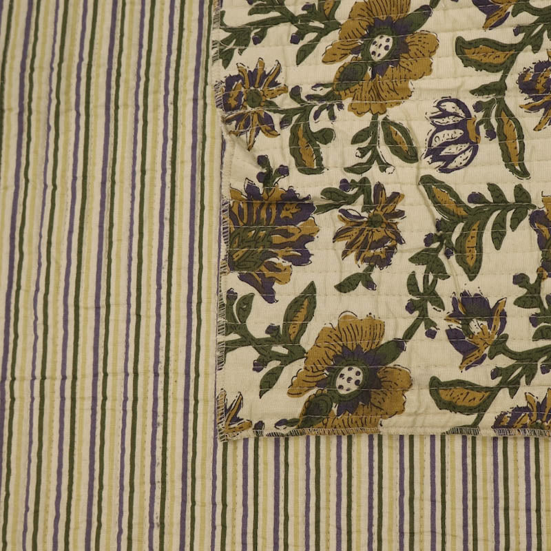 Quilted 100% Indian cotton fabric with a floral design in yellow, green and purple on a cream background on one side and a fine yellow and green stripe on a cream background on the reverse