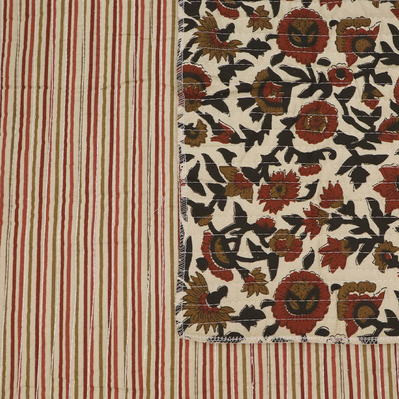 Quilted 100% Indian cotton fabric with a floral design in red, brown and black on a cream background on one side and a fine red and brown stripe on the reverse.