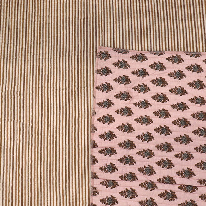 Quilted 100% Indian cotton fabric with a floral motif in brown and grey on a pale pink background on one side and a fine beige and cream stripe on the reverse.