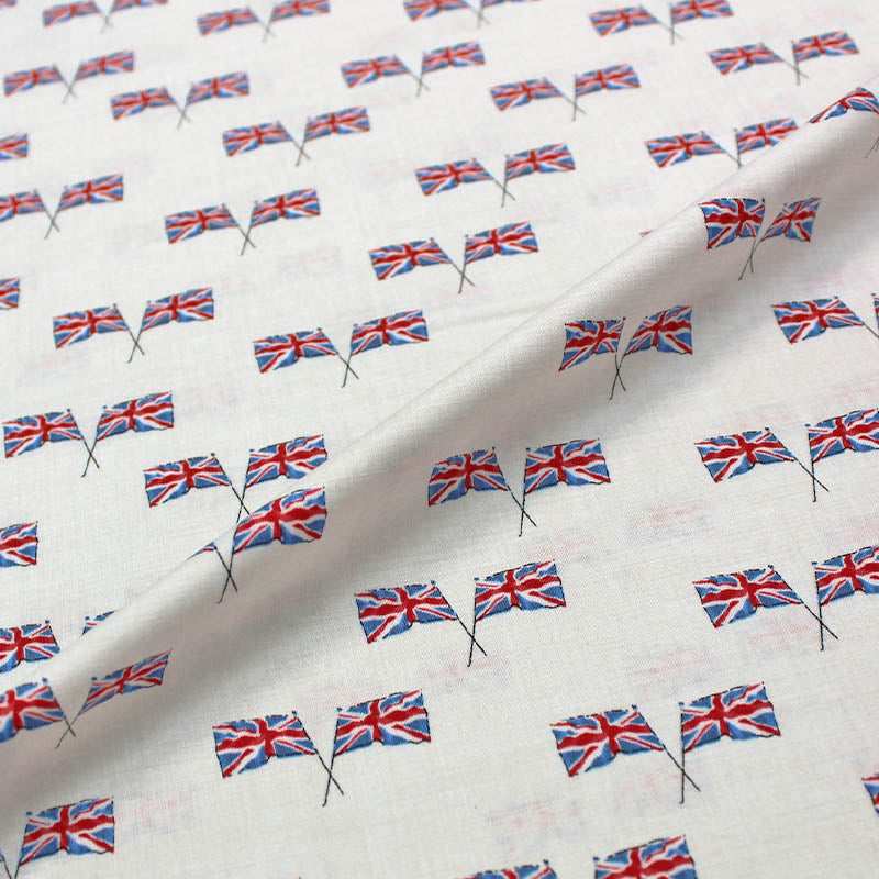 A fabric with a Union Jack print, featuring crossed flags of the UK on a cream background, suitable for bunting, patchwork, and quilting.