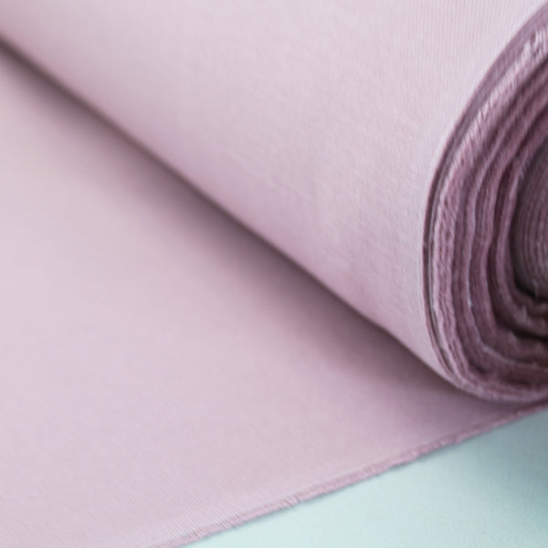 A rolled up piece of heather pink brushed cotton panama weave fabric.