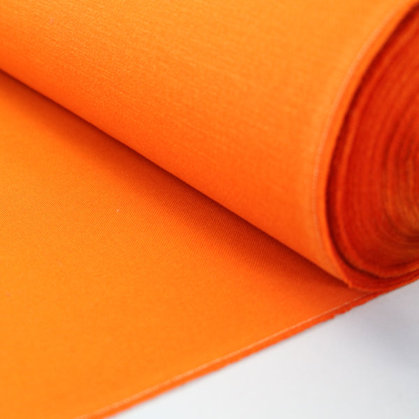 A rolled-up piece of spice orange furnishing fabric with a brushed panama weave texture.